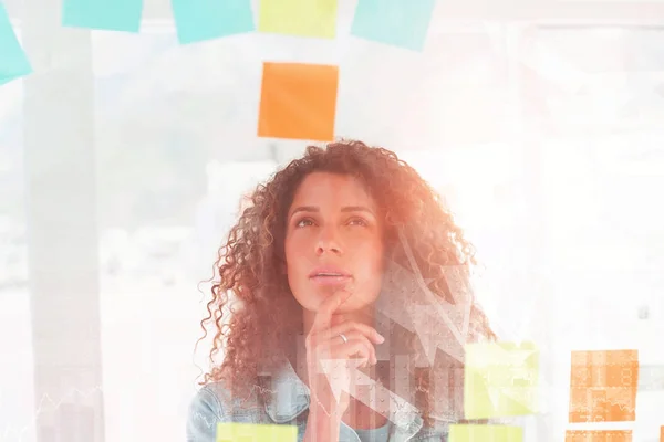 Designer looking at sticky notes on glass window — Stock Photo, Image