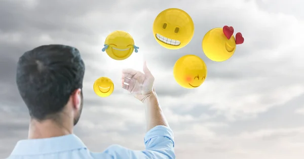 Baksidan av mannen håller upp glaset enhet mot molnig himmel med emojis och flare — Stockfoto