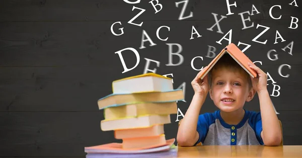 Pojke med boken på huvudet mot bokstäver som flyger i bakgrunden — Stockfoto