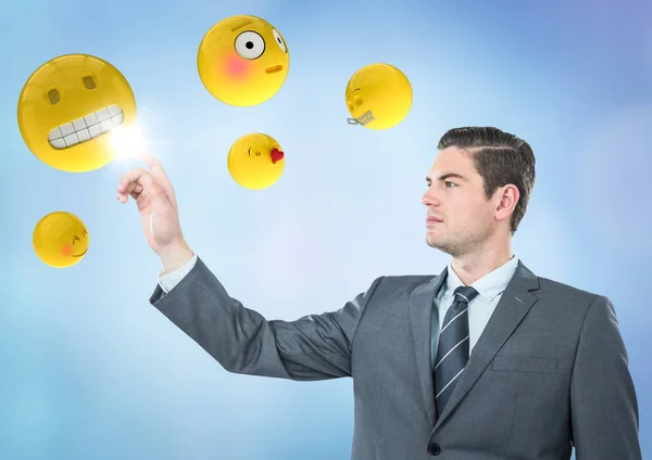 Geschäftsmann zeigt auf Emojis vor blauem Hintergrund — Stockfoto