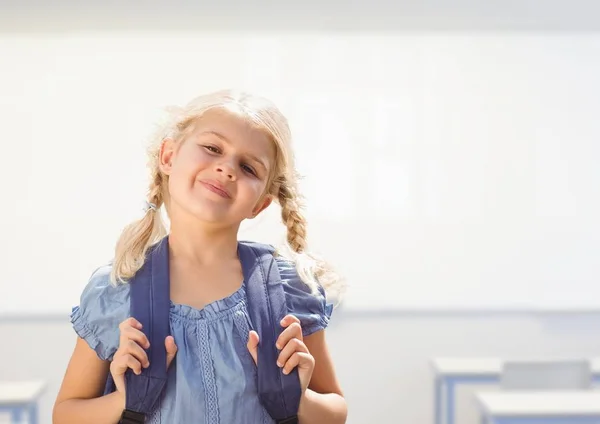 Junges Mädchen glücklich mit Tasche im Klassenzimmer — Stockfoto