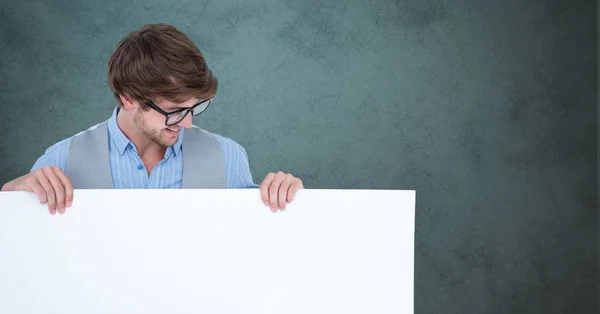 Hombre sonriente mirando la cartelera en blanco sobre fondo gris — Foto de Stock