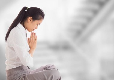 Business woman praying against blurry grey stairs clipart