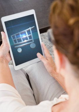 Tablet ile alışveriş arabası simgesi kullanan kadın