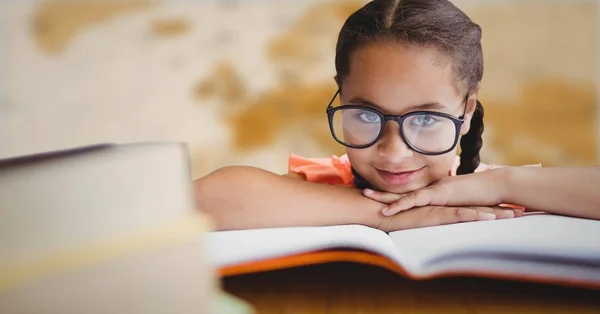 Dívka u stolu s knihami proti rozmazaný hnědá mapa — Stock fotografie