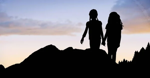 Silhouet meisjes hand in hand op berg tegen hemel — Stockfoto