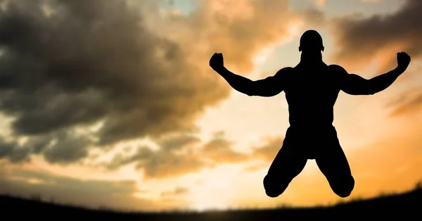 Silhueta homem muscular no ar contra o céu durante o pôr do sol — Fotografia de Stock