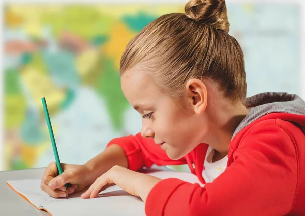 Menina fazendo lição de casa contra mapa desfocado — Fotografia de Stock