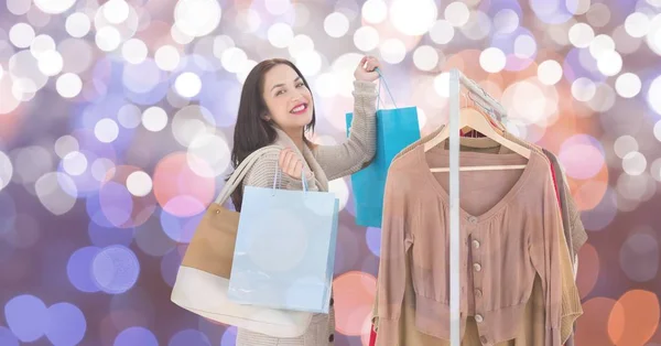 Feliz mulher compras por roupas rack sobre fundo borrado — Fotografia de Stock