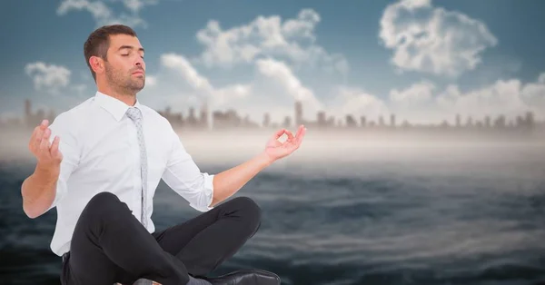 Business man meditating against water — Stock Photo, Image