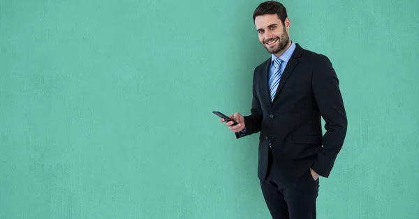 Uomo d'affari fiducioso utilizzando il telefono cellulare su sfondo verde — Foto Stock