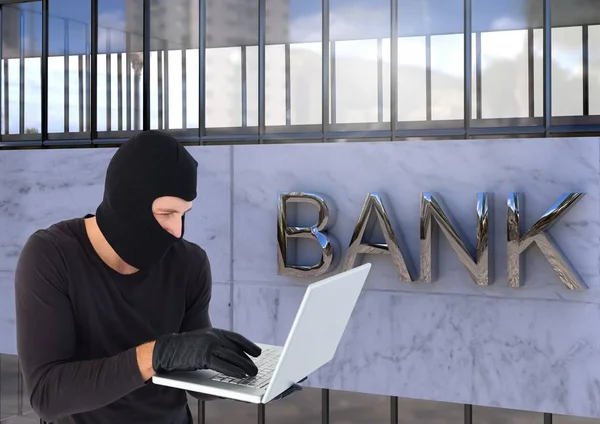 Zločinec v kapuce na notebooku před bankou — Stock fotografie