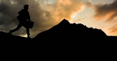 Dağ gökyüzü karşı çalışan siluet işadamı