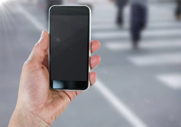 Mano con teléfono contra la calle borrosa con bengala — Foto de Stock