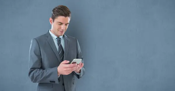 Empresario mensajes de texto en el teléfono inteligente contra la pared — Foto de Stock