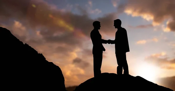 Бизнесмены силуэта пожимают друг другу руки на закате — стоковое фото