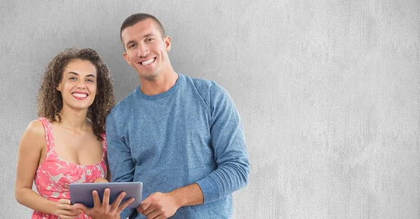 Smiling man and woman using tablet PC against wall — Stock Photo, Image