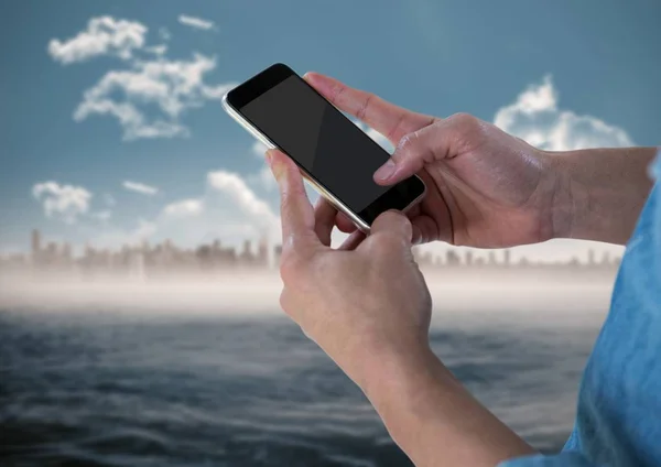 Händer med telefonen mot suddiga skyline — Stockfoto