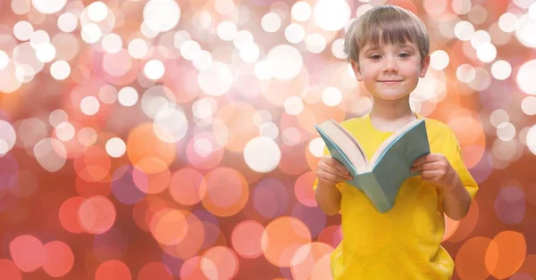 Söt pojke håller boken mot bokeh — Stockfoto