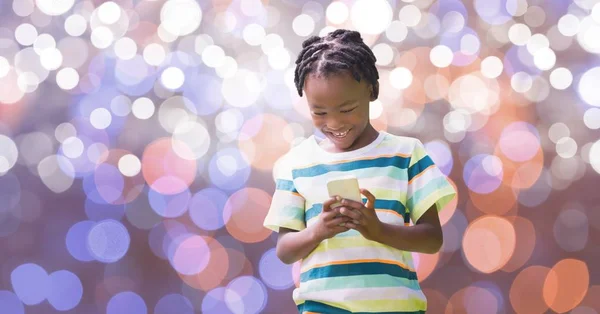 Happy boy using smart phone over bokeh — Stock Photo, Image