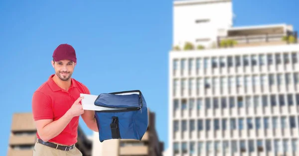 Delivery man removing pizza from bag in city — Stock Photo, Image