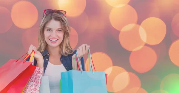 Lächelnde Frau mit bunten Einkaufstüten über Bokeh — Stockfoto