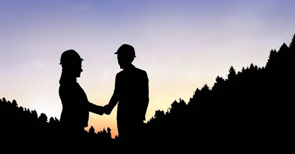 Силуэт бизнес-люди пожимают руки на горе во время заката — стоковое фото