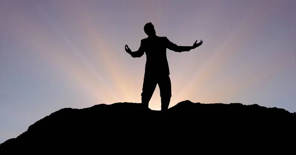 Silueta hombre de negocios con los brazos extendidos en la montaña durante la puesta del sol —  Fotos de Stock