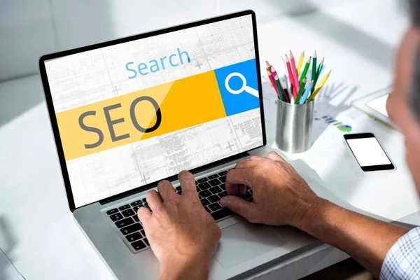 Mann arbeitet auf Laptop mit SEO-Wort — Stockfoto