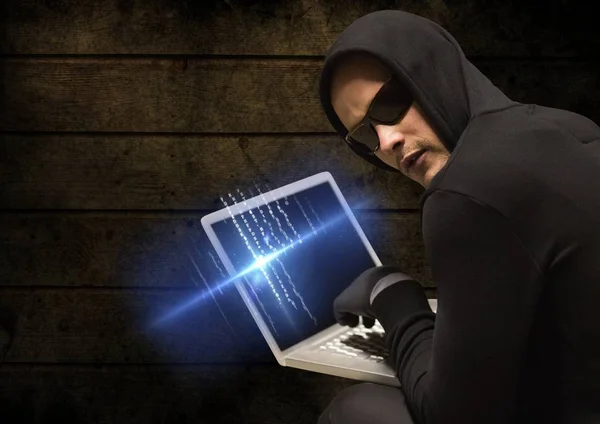Criminal in kap op laptop voor hout — Stockfoto