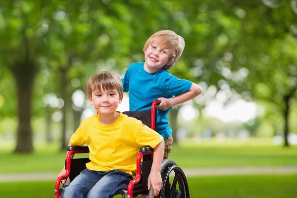 Boy pushing brother in wheel chair Stock Image