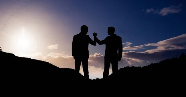 Бизнесмены держатся за руки в горах против неба — стоковое фото