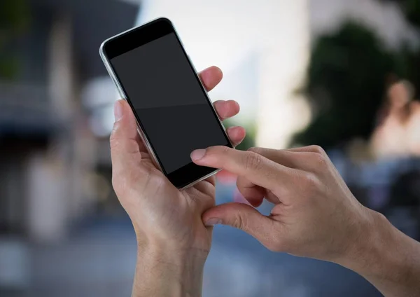 Manos con teléfono contra la calle borrosa — Foto de Stock