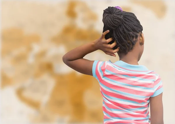 Costas de menina com a mão na cabeça contra o mapa marrom desfocado — Fotografia de Stock