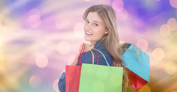 Lachende vrouw boodschappentassen uitvoering over de bokeh — Stockfoto