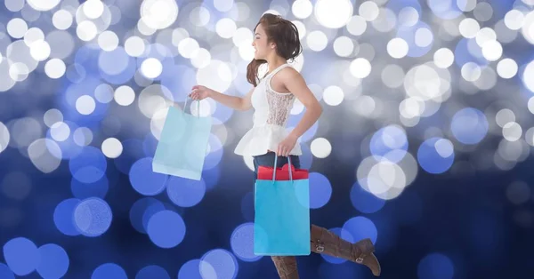 Vrouw met boodschappentassen tijdens het lopen tegen bokeh — Stockfoto