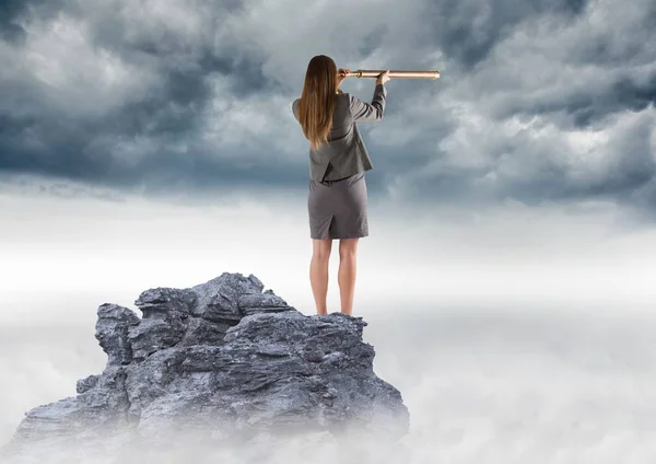 Mujer de negocios con telescopio en pico de montaña contra nubes de tormenta — Foto de Stock