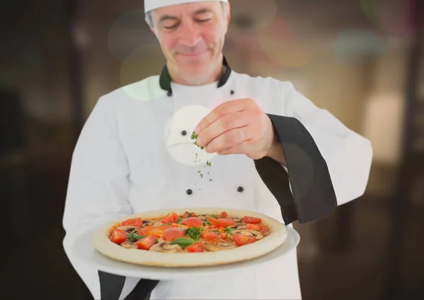 Chef vertiendo orégano a la pizza — Foto de Stock