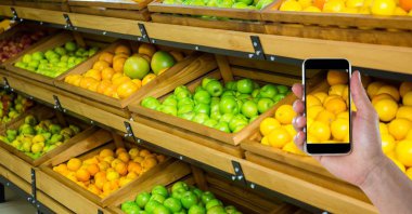 Meyve ve sebze deposundaki akıllı telefon üzerinde fotoğraf çekme el
