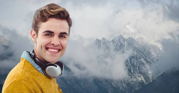 Hipster sorridente con cuffie contro montagne innevate — Foto Stock