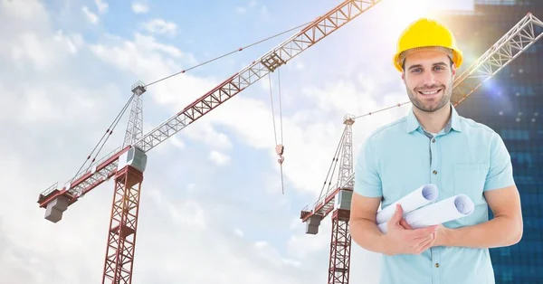 Arquiteto sorridente segurando plantas contra guindastes — Fotografia de Stock