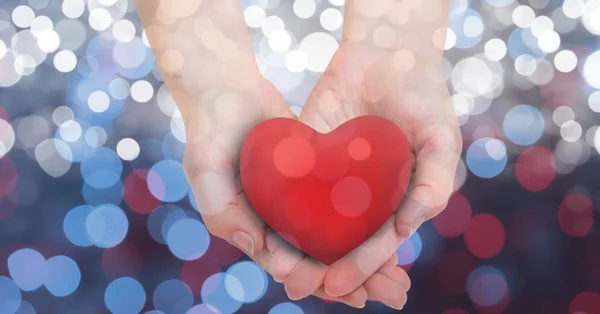 Female's hands holding heart shape over glowing bokeh — Stock Photo, Image