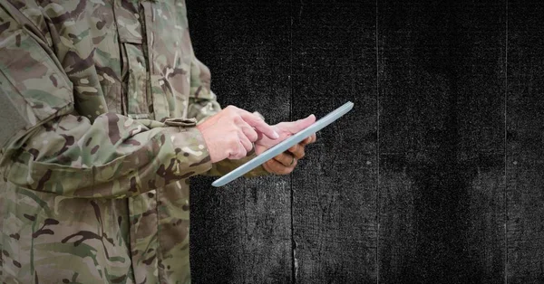 Soldado seção média com tablet contra painel de madeira preta — Fotografia de Stock