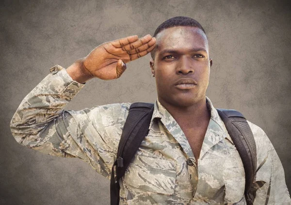 Soldier saluting against brown background — Stock Photo, Image