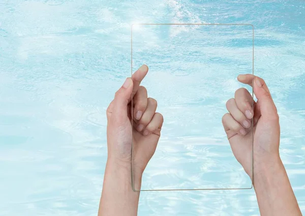Hand holding glass screen over clear blue water — Stock Photo, Image