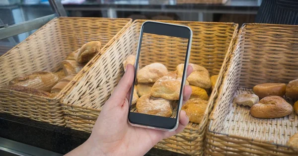 Pães de fotografar mão através de telefone inteligente no café — Fotografia de Stock