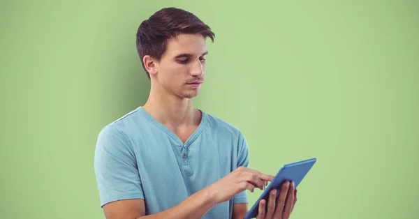 Hombre joven usando tableta sobre fondo verde —  Fotos de Stock