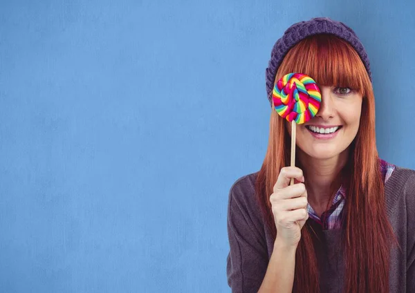 Feliz fêmea hipster cobrindo olho com doces contra fundo azul — Fotografia de Stock