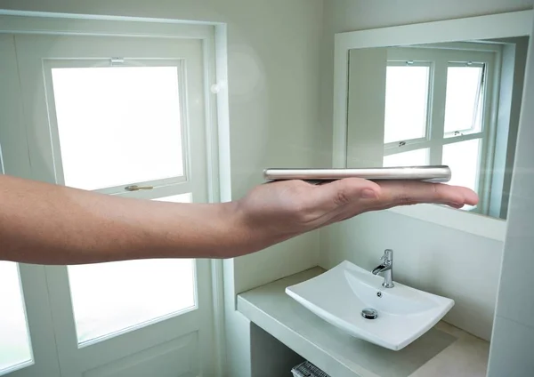 Рука тримає телефон у ванній — стокове фото