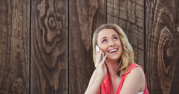 Mulher feliz usando telefone inteligente contra parede de madeira — Fotografia de Stock